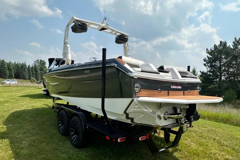 Slide: The Image of 2026 Nautique Super Air Nautique GS22E boat on trailer, parked on grassy field. - 29