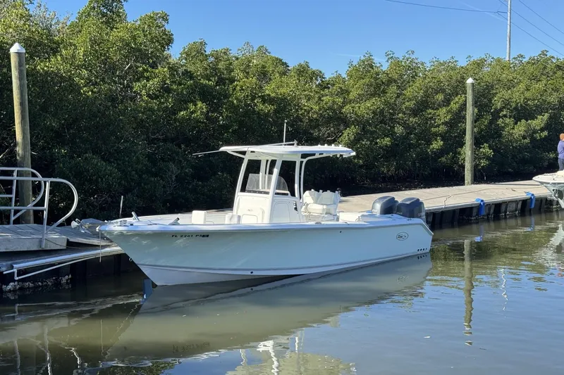 Slide: The Image of 2014 Sea Hunt Gamefish 25 boat docked by lush greenery. - 0