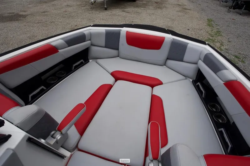 Slide: The Image of 2021 Malibu M220 boat interior with red and gray seating, cup holders, and armrests. - 3
