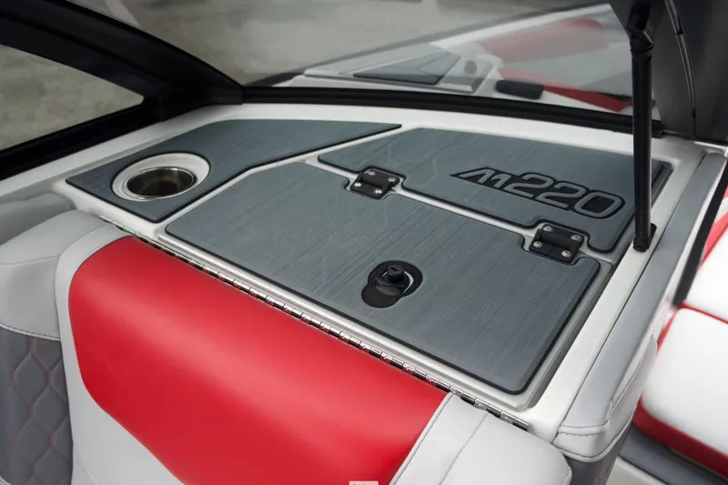 Slide: The Image of 2021 Malibu M220 boat interior with red and gray seating, cup holder, and storage compartment. - 4