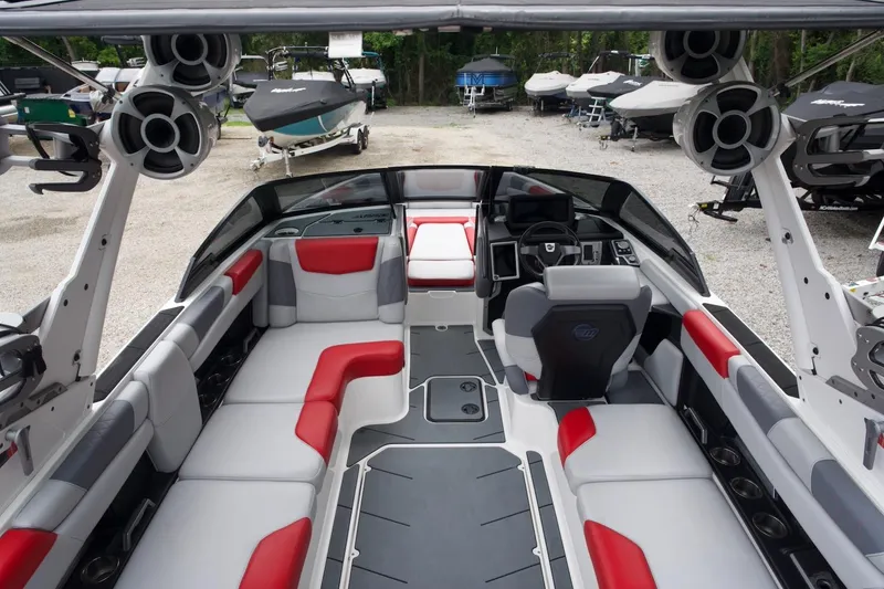 Slide: The Image of 2021 Malibu M220 boat interior with red and gray seating, advanced dashboard, and speakers. - 9
