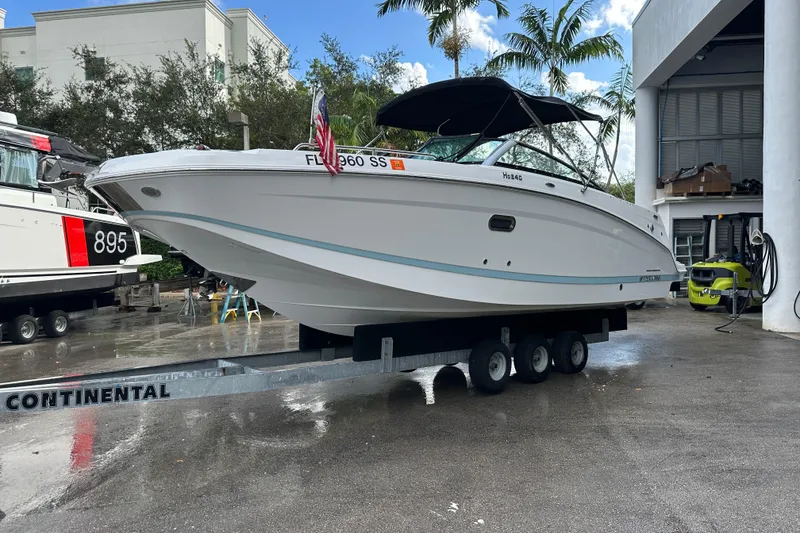 Slide: The Image of 2020 Four Winns HD240 OB boat on trailer, parked outdoors near palm trees. - 60