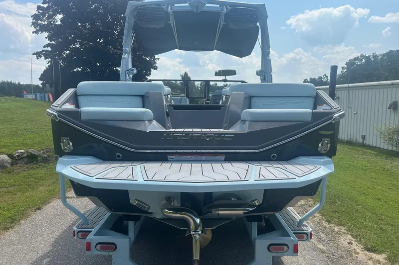Slide: The Image of 2026 Nautique Super Air Nautique G23 boat rear view on trailer, sunny day. - 5