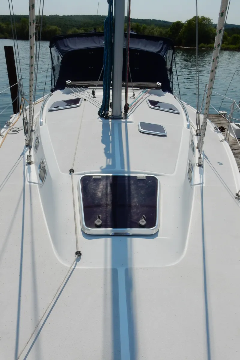 Slide: The Image of 2004 Catalina 350 sailboat deck with hatch, docked on calm water. - 10