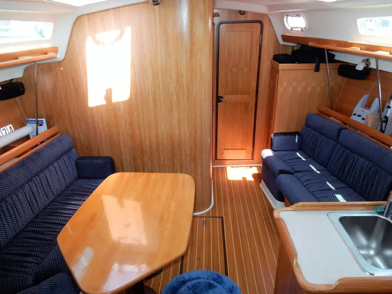 Slide: The Image of Interior of 2004 Catalina 350 sailboat with wooden furnishings and blue upholstered seating. - 18
