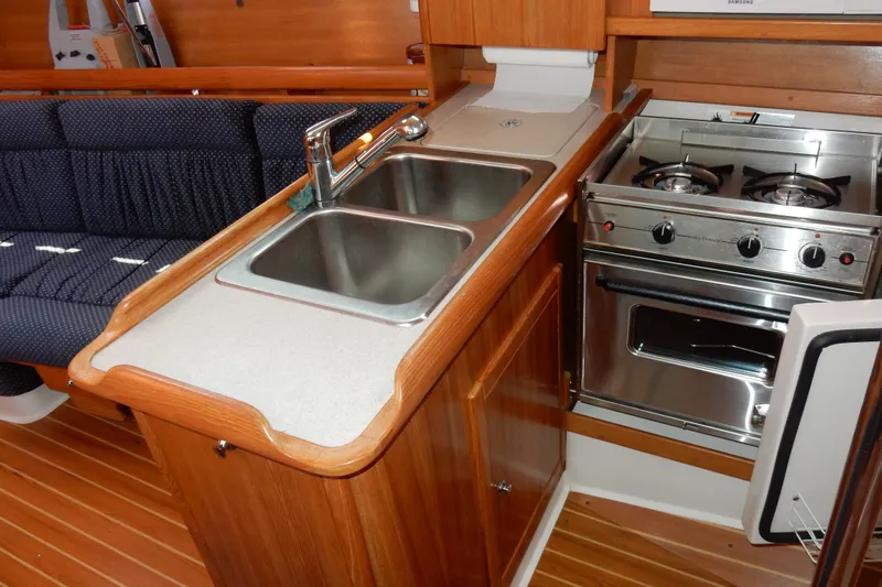 Slide: The Image of 2004 Catalina 350 yacht interior kitchen with dual sink, stove, and wooden cabinetry. - 21