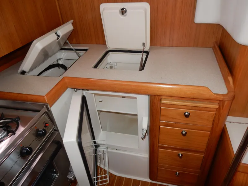 Slide: The Image of 2004 Catalina 350 yacht kitchen with stove, fridge, and wooden cabinetry. - 24
