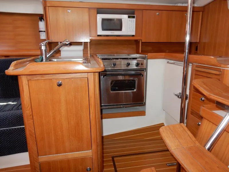 Slide: The Image of 2004 Catalina 350 yacht kitchen with wood cabinetry, stainless steel oven, and microwave. - 27