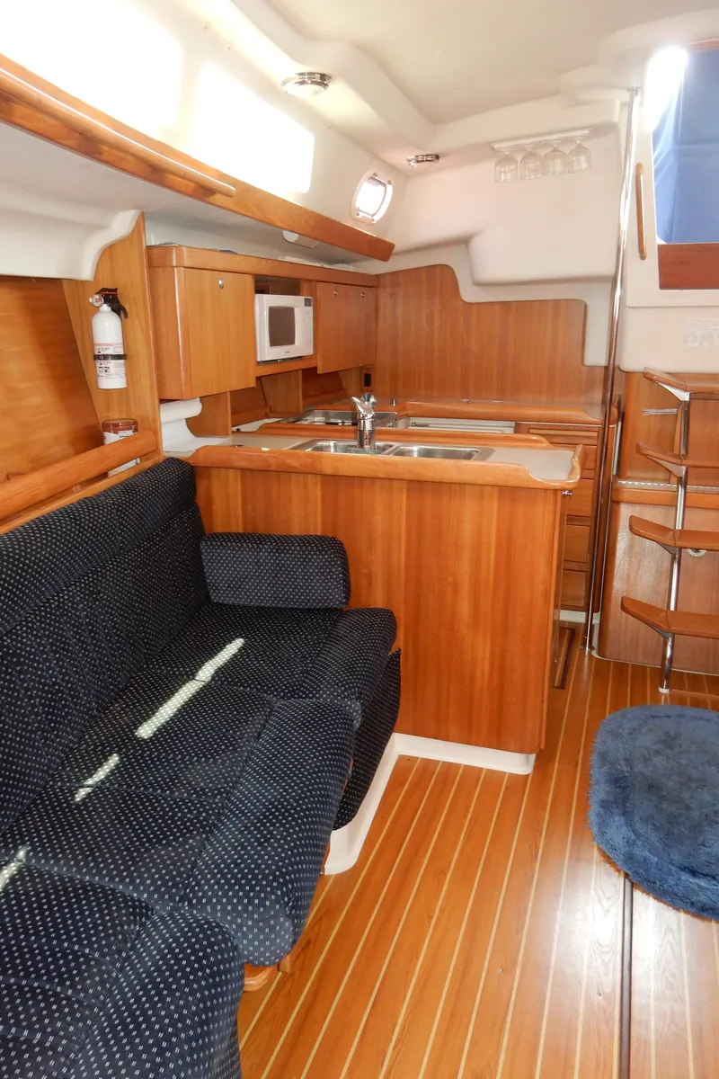 Slide: The Image of 2004 Catalina 350 yacht interior with wooden cabinetry, kitchenette, and seating area. - 29