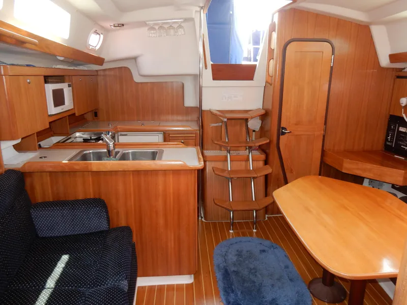 Slide: The Image of 2004 Catalina 350 yacht interior with wooden cabinetry, kitchen, and dining area. - 30