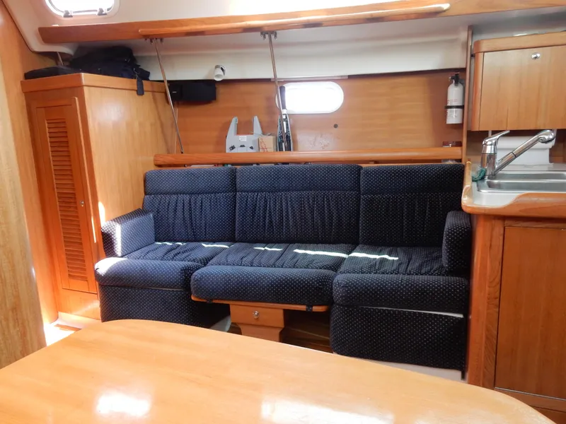 Slide: The Image of Interior of 2004 Catalina 350 sailboat with blue sofa, wooden cabinetry, and compact kitchen area. - 32