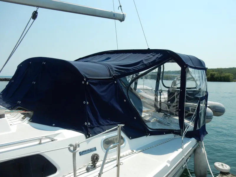 Slide: The Image of 2004 Catalina 350 sailboat with blue canvas cover docked on a sunny day. - 4