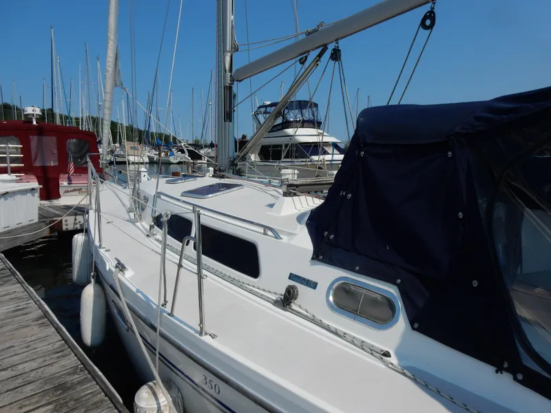 Slide: The Image of 2004 Catalina 350 sailboat docked at marina, featuring sleek design and blue canopy. - 6
