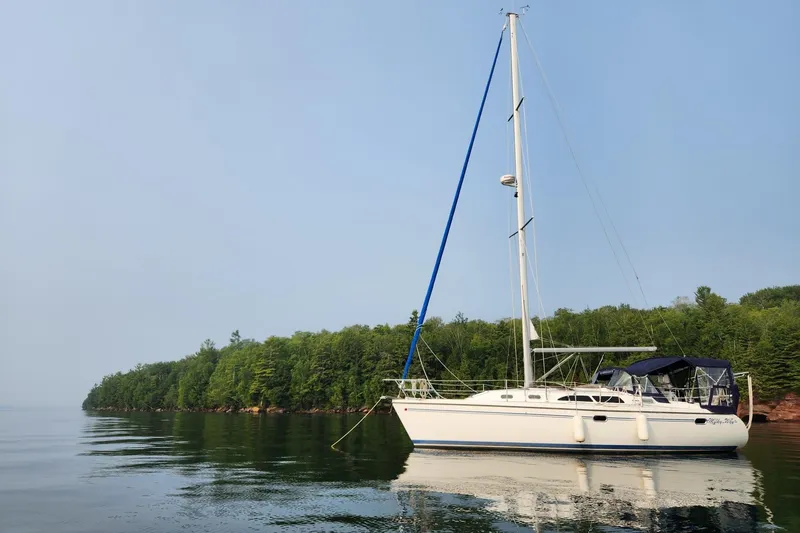 Slide: The Image of Catalina 350 sailboat from 2004 anchored near a lush, green shoreline. - 76