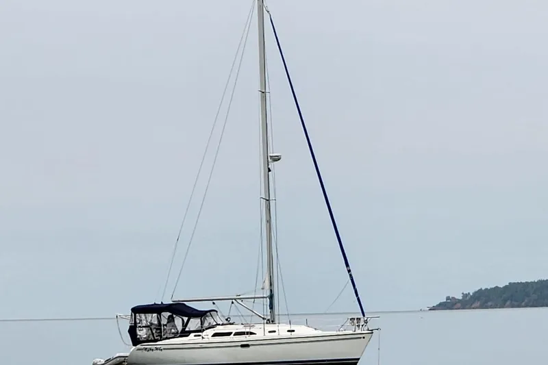 Slide: The Image of 2004 Catalina 350 sailboat anchored on calm water with distant shoreline. - 77