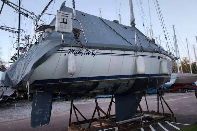 Slide: The Image of 2004 Catalina 350 sailboat named "Milkey Way" on a stand, covered and docked. - 82