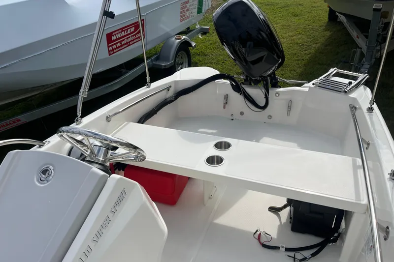 Slide: The Image of 2026 Boston Whaler 130 Super Sport boat interior with steering wheel and motor. - 12