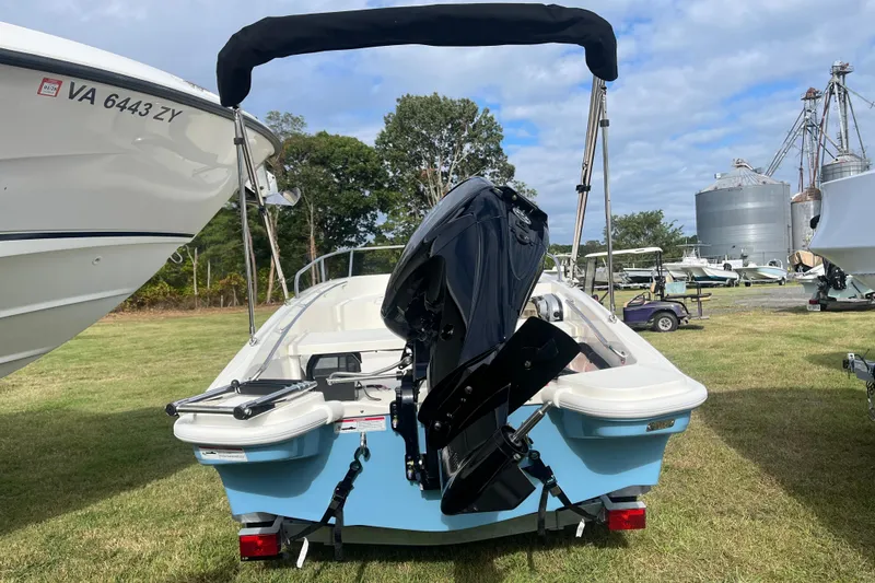 Slide: The Image of 2026 Boston Whaler 130 Super Sport boat with outboard motor, parked on grass. - 19
