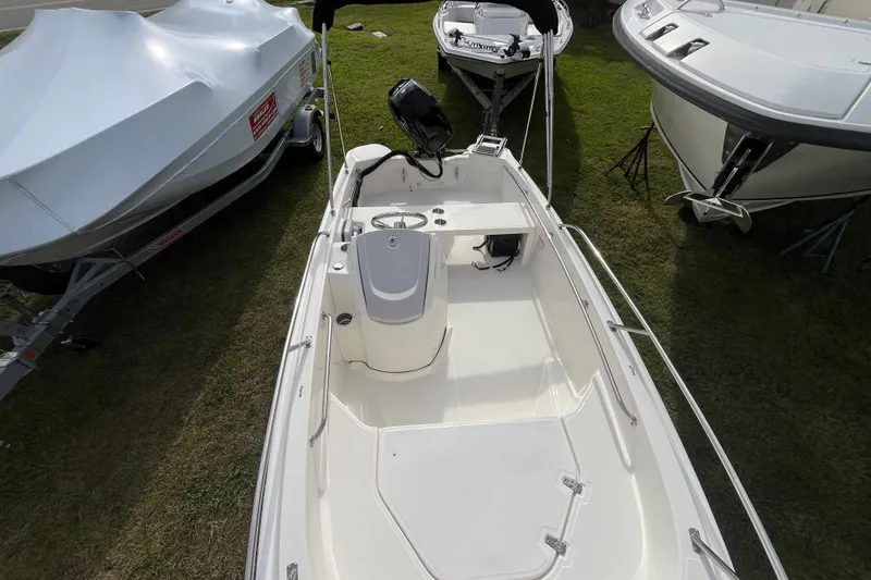 Slide: The Image of 2026 Boston Whaler 130 Super Sport boat displayed outdoors, surrounded by other boats. - 4