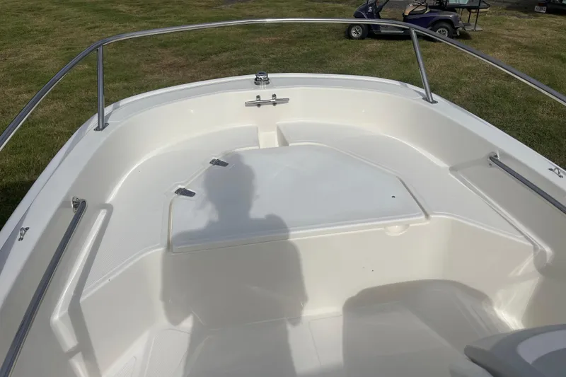 Slide: The Image of 2026 Boston Whaler 130 Super Sport boat interior with white seating and stainless steel railings. - 5