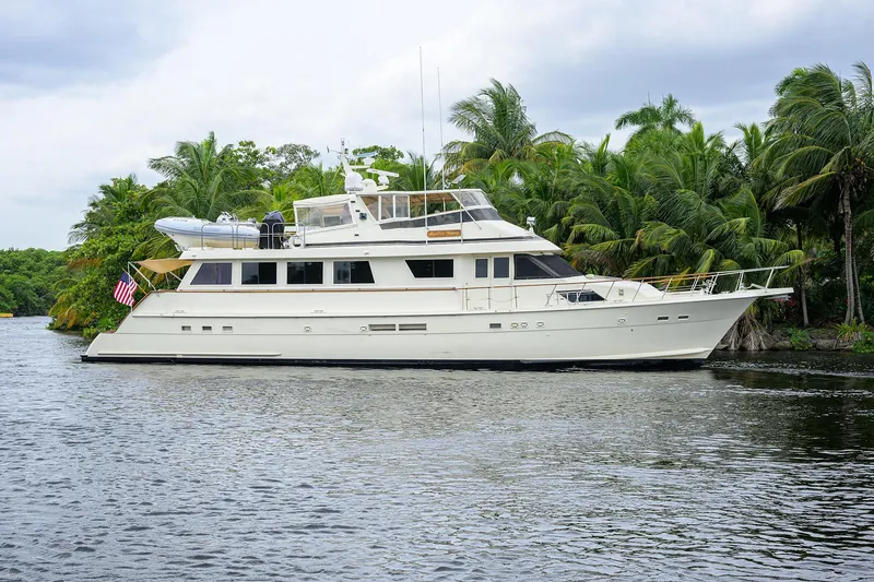 Slide: The Image of 1991 Hatteras 78 CMY yacht cruising on a tropical river with lush greenery. - 0