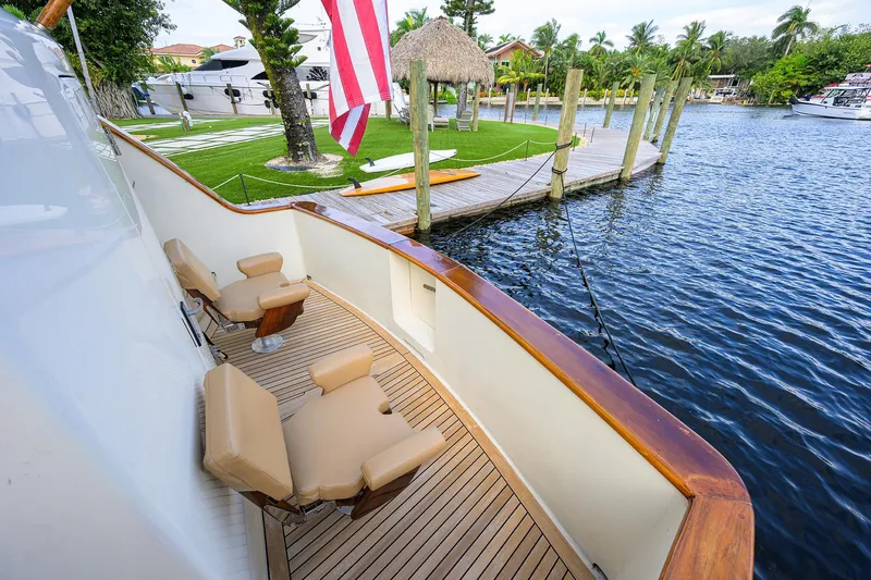 Slide: The Image of 1991 Hatteras 78 CMY yacht deck with chairs, docked by a scenic waterfront. - 13