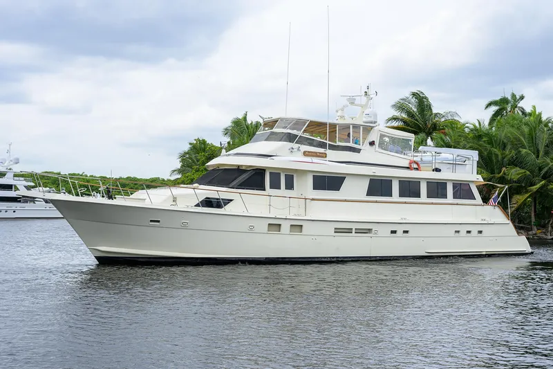 Slide: The Image of 1991 Hatteras 78 CMY yacht on calm water, surrounded by lush greenery. - 7