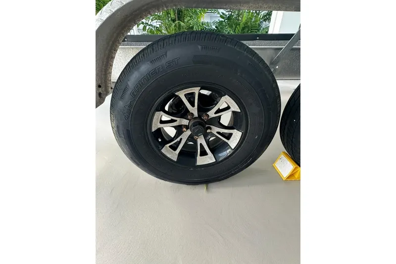 Slide: The Image of Trailer wheel with black tire and silver rim, parked on concrete surface. - 13