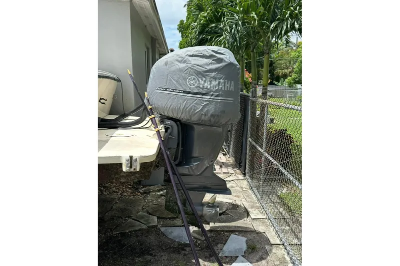 Slide: The Image of 2007 Parker 2501 Center Console with Yamaha outboard motor covered, near a fence and greenery. - 6