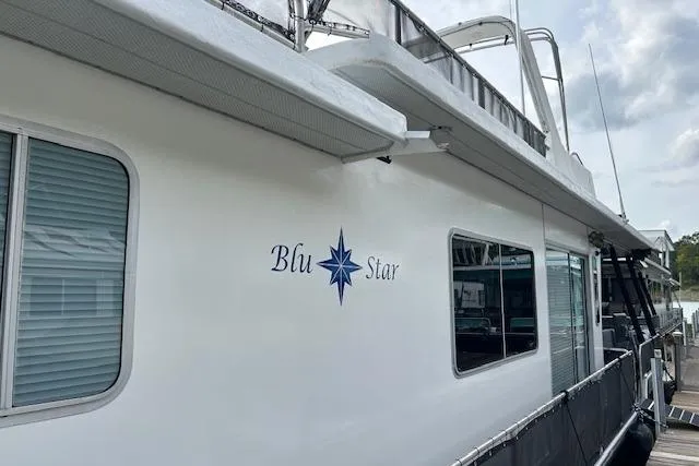 The Image of 1987 Sumerset 14x60 houseboat docked, featuring outdoor seating and scenic lake backdrop. - 0