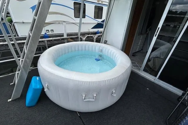 Slide: The Image of 1987 Somerset Houseboat 14X60 deck with hot tub and lounge chairs, docked by the water. - 15