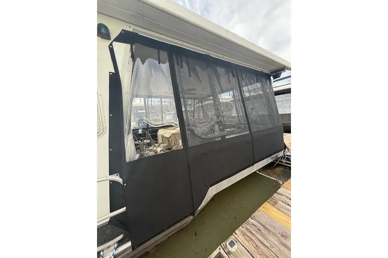 Slide: The Image of 1987 Sumerset 14x60 houseboat docked, featuring upper deck and American flag. - 2