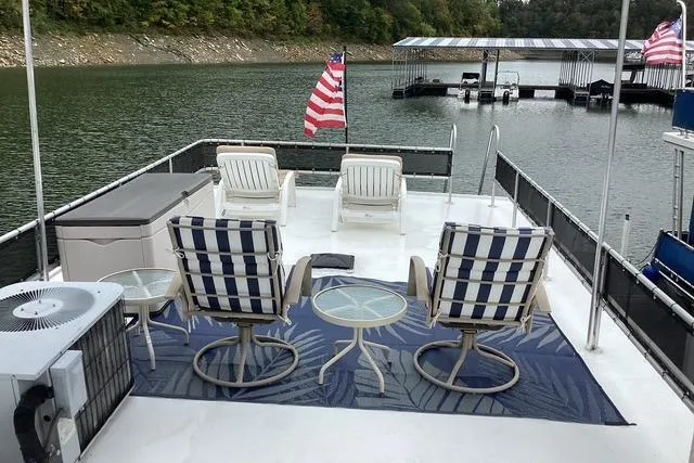 Slide: The Image of 1987 Sumerset 14x60 houseboat deck with chairs, tables, and American flags on a lake. - 38