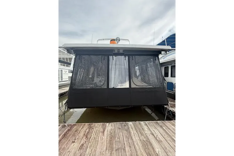 Slide: The Image of 1987 Somerset Houseboat 14X60 at dusk, illuminated with string lights, against a wooded backdrop. - 4