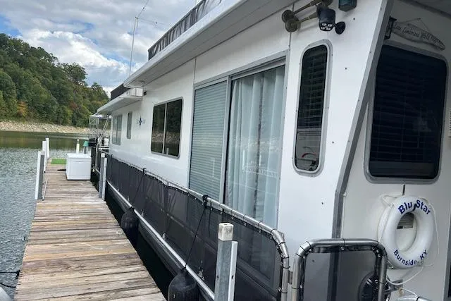 Slide: The Image of 1987 Sumerset 14x60 houseboat cruising on a lake with forested hills in the background. - 6