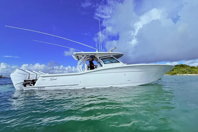 The Image of 2024 Scout 400 LXF boat on clear water under a blue sky. - 0