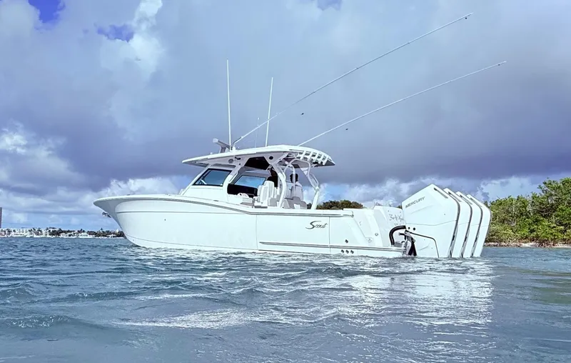 Slide: The Image of 2024 Scout 400 LXF boat on water with triple Mercury engines, under cloudy sky. - 17