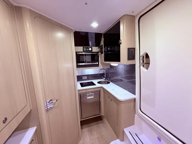 Slide: The Image of 2024 Scout 400 LXF boat interior kitchen with modern appliances and sleek design. - 51