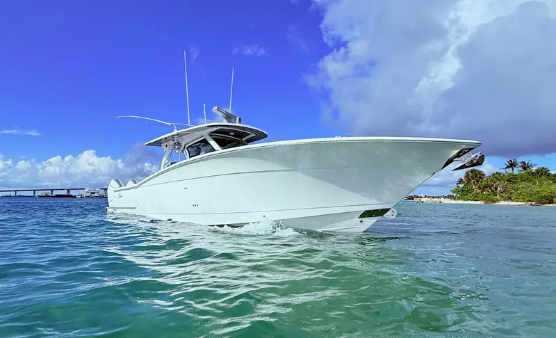 Slide: The Image of 2024 Scout 400 LXF boat cruising in clear blue waters under a vibrant sky. - 9