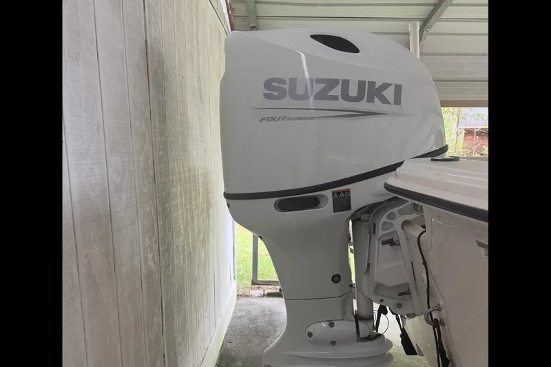 Slide: The Image of 2022 Carolina Skiff 19 LS boat interior with seating and console, parked on a driveway. - 7