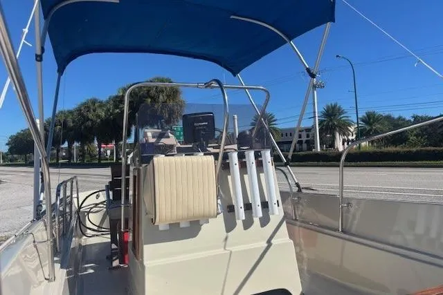 Slide: The Image of 1987 Boston Whaler 170 Montauk boat with blue canopy, parked near palm trees. - 2