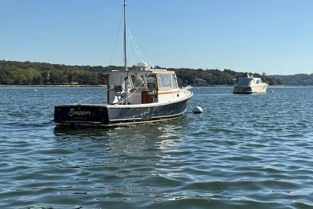 Slide: The Image of 1975 Jarvis Newman 32 DEC boat anchored on calm water with scenic background. - 2