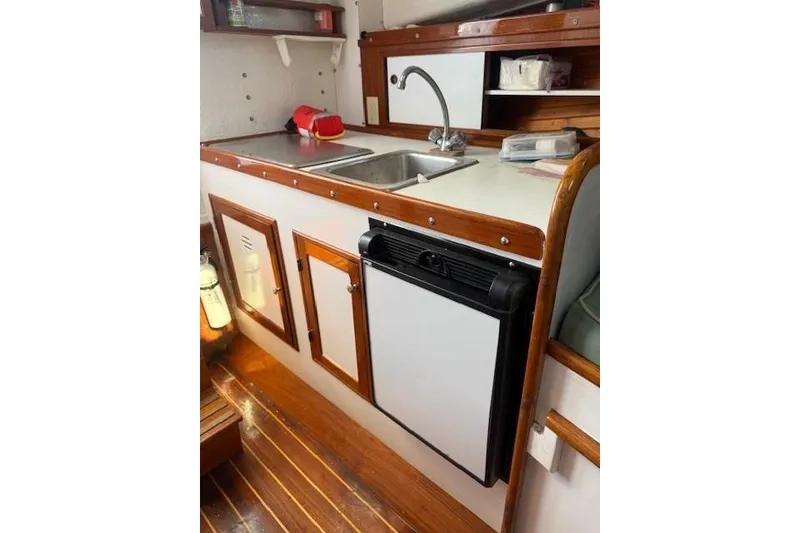 Slide: The Image of 1975 Jarvis Newman 32 DEC boat kitchen with sink, fridge, and wooden cabinetry. - 45