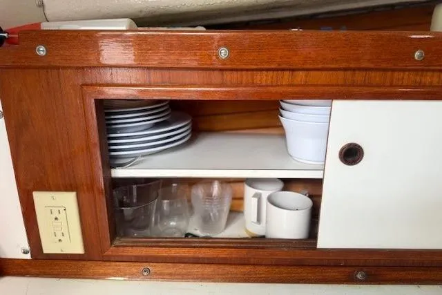 Slide: The Image of 1975 Jarvis Newman 32 DEC boat interior with wooden cabinet, dishes, and mugs. - 49