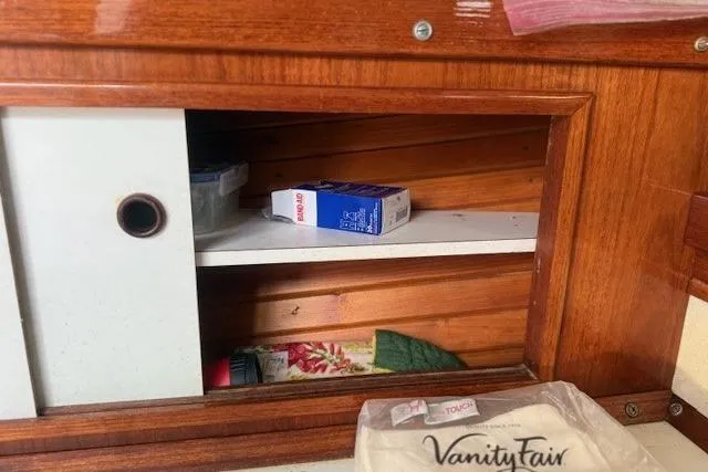 Slide: The Image of Wooden cabinet interior on a 1975 Jarvis Newman 32 DEC boat, with stored items. - 50