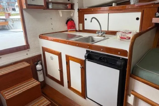 Slide: The Image of 1975 Jarvis Newman 32 DEC boat interior with kitchenette, sink, and wooden cabinetry. - 52