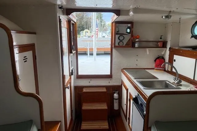 Slide: The Image of Interior of a 1975 Jarvis Newman 32 DEC boat, featuring a compact kitchen and wooden accents. - 65