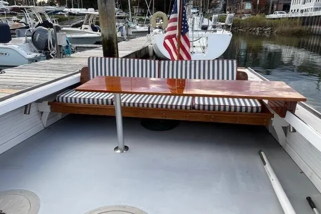 Slide: The Image of 1975 Jarvis Newman 32 DEC boat with striped seating and wooden table at a marina. - 68
