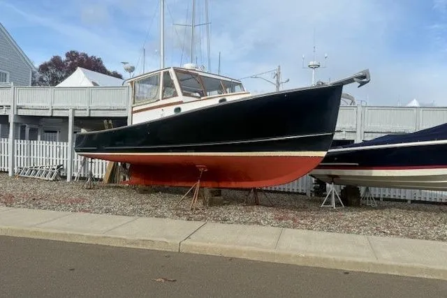 Slide: The Image of 1975 Jarvis Newman 32 DEC boat on display, black hull with red bottom, docked on land. - 71