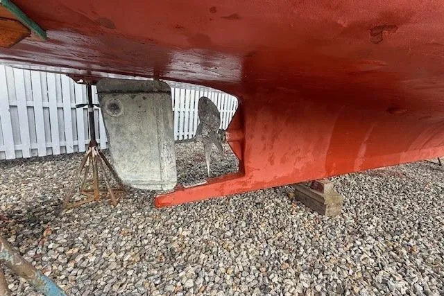 Slide: The Image of 1975 Jarvis Newman 32 DEC boat hull with visible propeller and rudder on gravel. - 73